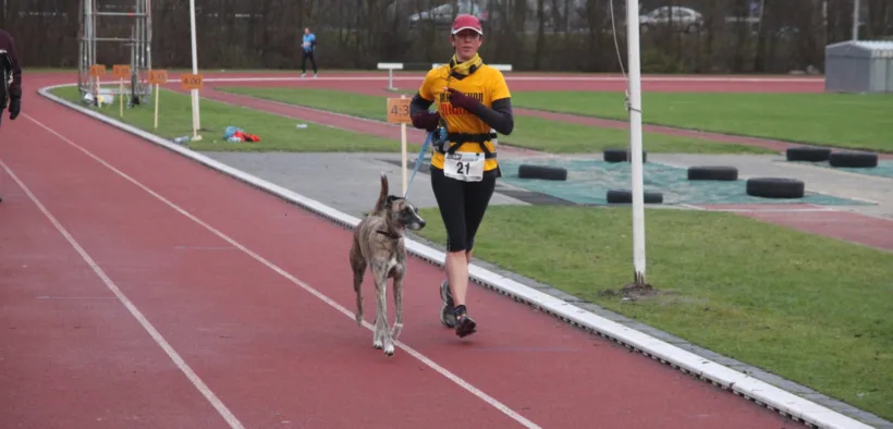 Mujer corre una carrera acompañada por un perro