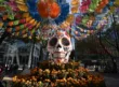 Calavera monumental sobre flores de cempasúchil bajo papel picado en la Ciudad de México