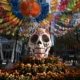Calavera monumental sobre flores de cempasúchil bajo papel picado en la Ciudad de México