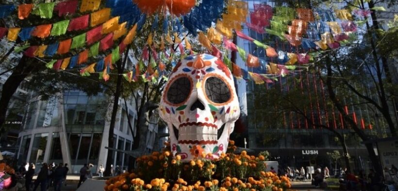 Calavera monumental con papel picado y flores de cempasúchil en un camellón de la Ciudad de México