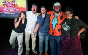 Cinco artistas participantes en el Encuentro Internacional de Clown posan frente a la imagen del festival