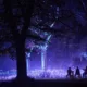 Árboles iluminados con luces azules y moradas y visitantes sentados en un recorrido nocturno de Light Cycles