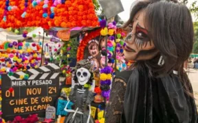 Visitante caracterizada de catrina junto a una ofrenda en la Megaofrenda UNAM