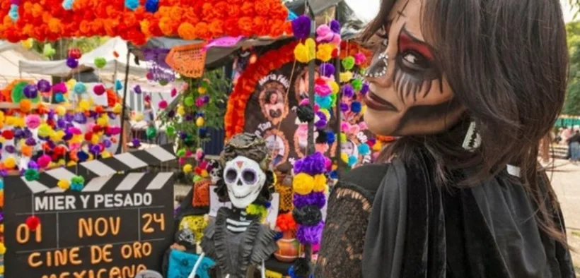Visitante caracterizada de catrina junto a una ofrenda en la Megaofrenda UNAM