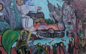 Mural con flores, mazorcas y figuras humanas en un muro del Mercado de Jamaica.