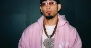 Retrato de Omar Courtz con sudadera rosa, lentes y cadenas