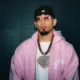 Retrato de Omar Courtz con sudadera rosa, lentes y cadenas