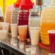 Vitroleros y vasos con bebidas tradicionales de colores sobre la barra de un puesto mexicano