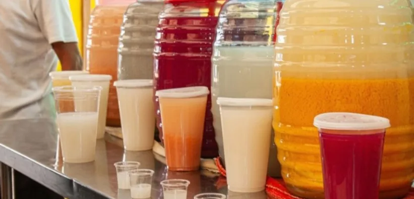 Vitroleros y vasos con bebidas tradicionales de colores sobre la barra de un puesto mexicano