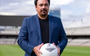 Hugo Sánchez sostiene un balón en la cancha del Estadio Olímpico Universitario