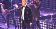Robbie Williams canta durante un concierto con un micrófono en la mano