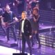 Robbie Williams canta durante un concierto con un micrófono en la mano