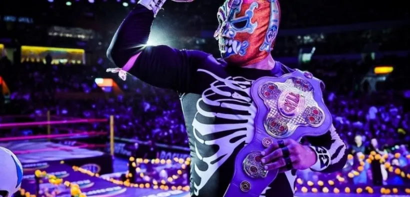 Luchador del CMLL con atuendo de esqueleto y cinturón de campeón en la Arena México decorada por Día de Muertos