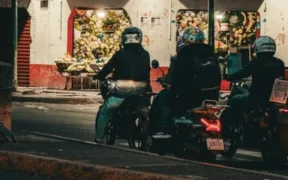 Motociclistas detenidos frente a una florería iluminada en una calle de noche