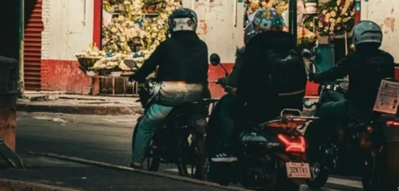 Motociclistas detenidos frente a una florería iluminada en una calle de noche