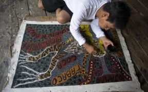 El artista Santiago Yahuarcani trabaja sobre una pintura en su taller