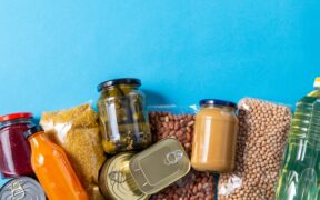 eating, charity and donation concept - close up of different packed food on blue background
