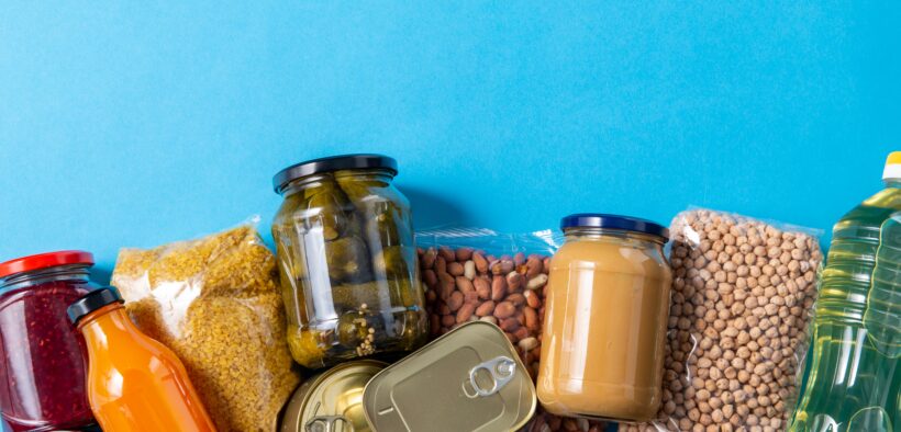 eating, charity and donation concept - close up of different packed food on blue background