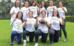 Jugadoras de UNAM Azul posan con playeras de campeonas y un balón de futbol americano